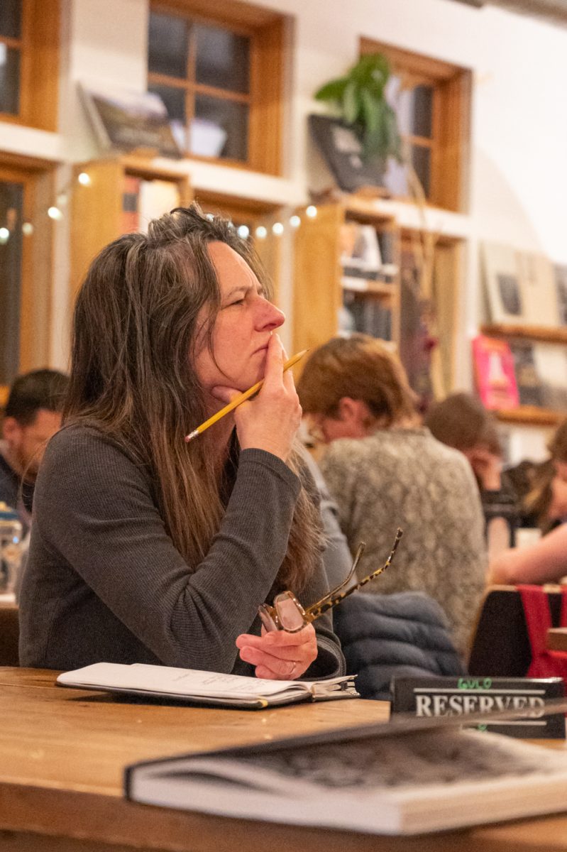 Mallory Graham, a newcomer to Fort Collins who joined the event to meet new people, sits in contemplation of the book titles around the room Mar. 3. Her poem for the night was written entirely from the titles of books around the room, put together in such a way to form a coherent message. “Fort Collins’ is on fire with poetry, like, it is so cool,” Graham said. “I think it is a hard time to be living right now and to just be inspired by a group of people who are all about writing and poems and sharing, very, very cool.”