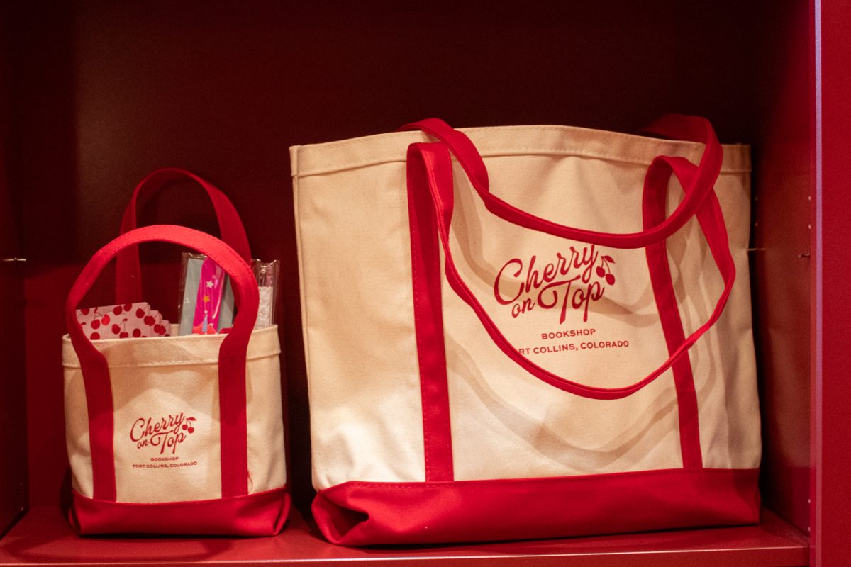 Tote bags, displayed on a book case, feature the logo of Cherry On Top, a new bookstore in Downtown Fort Collins Mar. 5. The romance-only bookshop is co-owned and run by friends and Fort Collins Locals Devon Beuret and Meredith Glover. “We are working on getting events going, so we’re gonna have, like, community events and we’ve had lots of requests for book clubs,” Glover said.