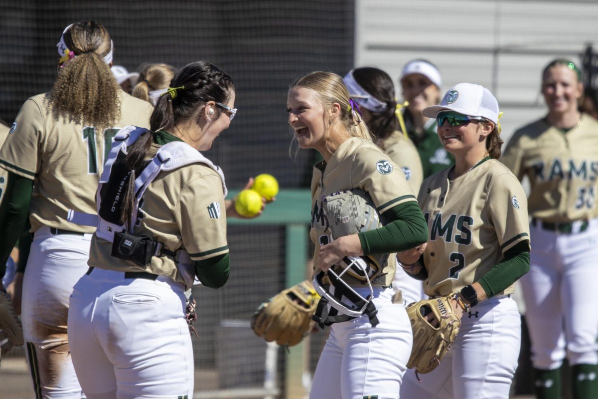 Abby Edwards (34) and Jac Smith (2) congratulate Regan Wick (12) on pitching during Colorado State University’s game against South Dakota State March 8. The Rams secured an 8-0 shutout in five innings at the CSU Softball Field.