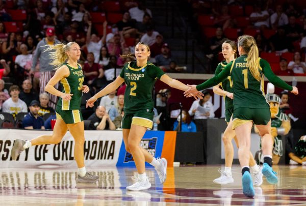A group of four women wearing all green jerseys clap hands together as they backpedal.