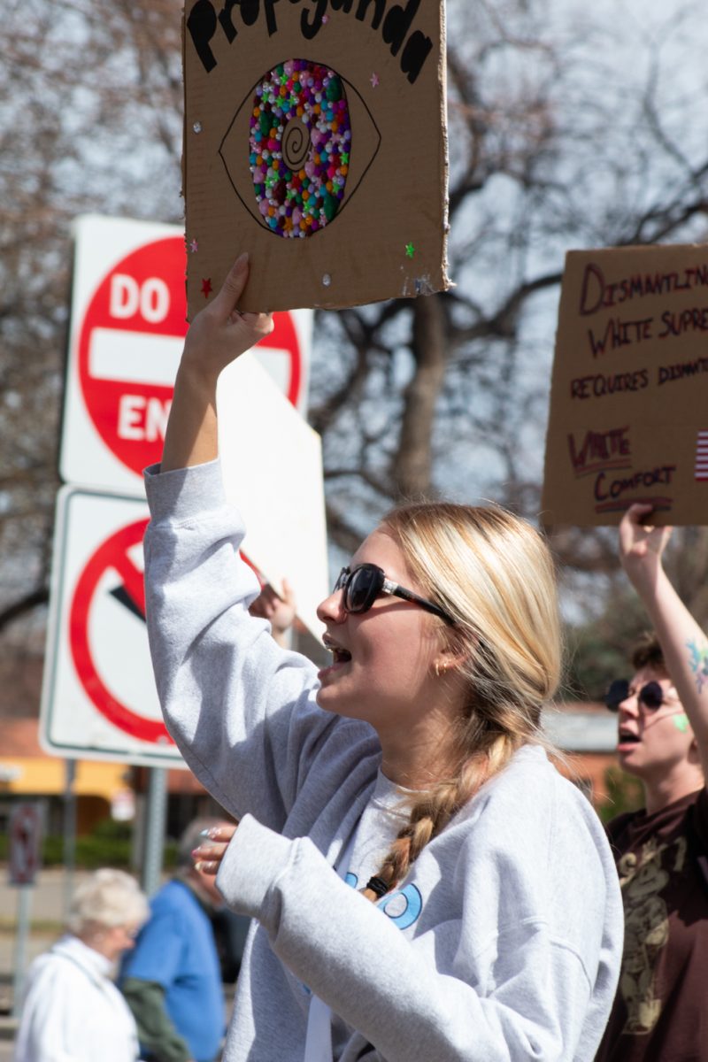 A No Kings protester walks down Olive street, raising their sign while leading others in a chant March 28. As part of the third No Kings rally, these attendees marched through Fort Collins protesting the actions of the Trump Administration. “Whose streets? Our streets!” the protesters chanted.