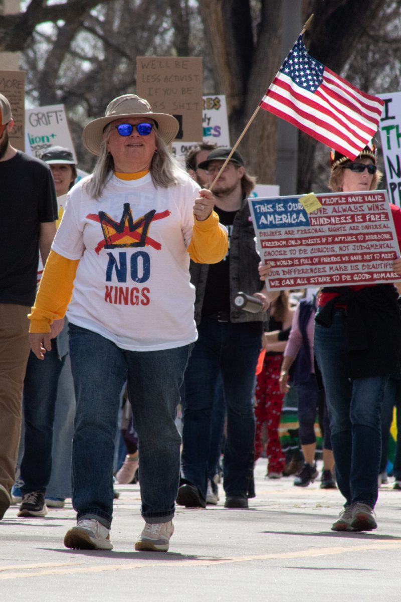 A No Kings protester waves an American flag while walking up North Howes street towards Civic Center Park March 28. This attendee was one of roughly 10,000 who showed up to attend the No Kings protest, where people in cities across the country expressed their dissatisfaction with the Trump administration. “When immigrant rights are under attack, what do we do? Stand up, fight back!” protesters chanted.