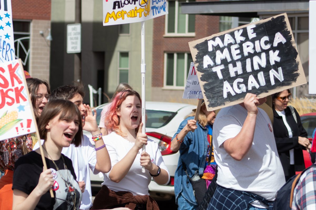 No Kings protesters raise their signs and shout while marching along Maple Street March 28. As part of the third No Kings rally, an estimated 10,000 attendees listened to speeches and music in Civic Center Park before marching through Fort Collins, protesting the actions of the Trump Administration. “Show me what America looks like! This is what America looks like!” the protesters chanted.