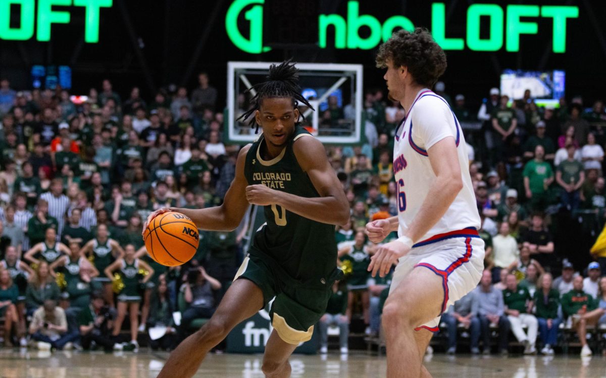 A man in an all green jersey runs with the ball in his right hand, he is leaning on a man in an all white jersey to his left.