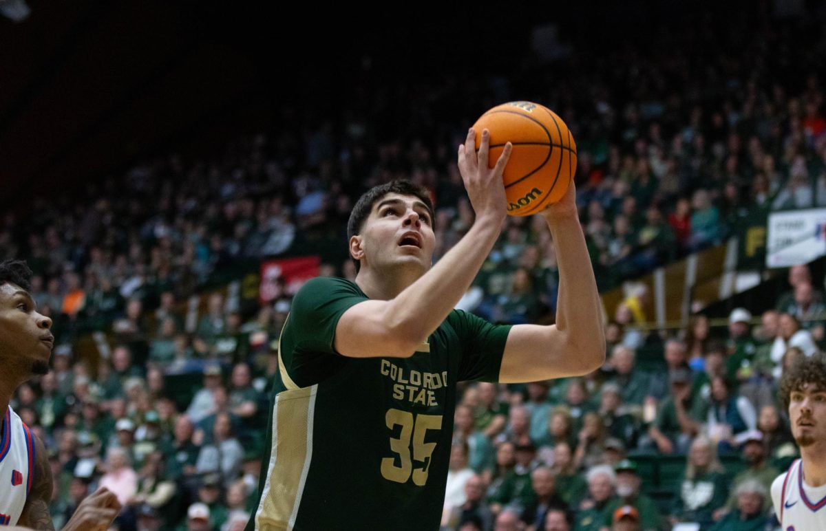 A man in an all green jersey holds the ball above his head with both hands as he looks up as well.