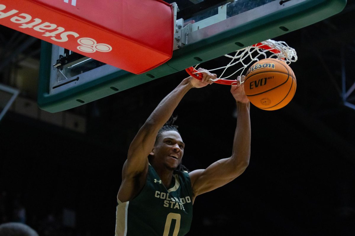 A man in an all green jersey extends both of his hands to the rim, the ball is falling through the rim.