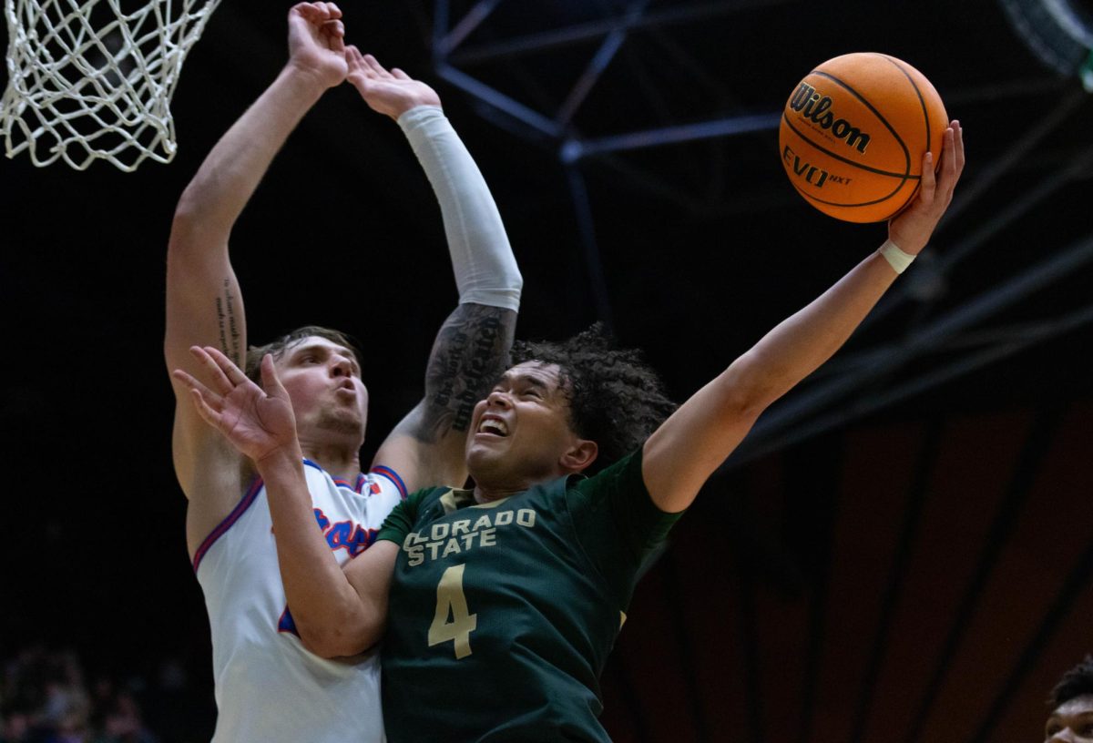 A man in an all green jersey jumps into a man in an all white jersey. The man in green holds the ball away from the man in white with his left hand, the man in white has both of his hands in the air.