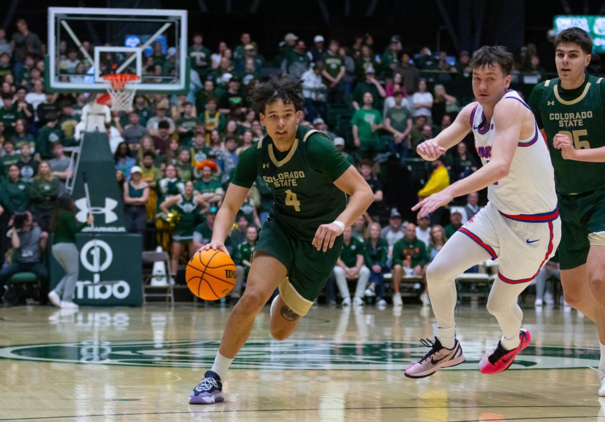 A man in an all green jersey runs forward with the ball in his right hand.