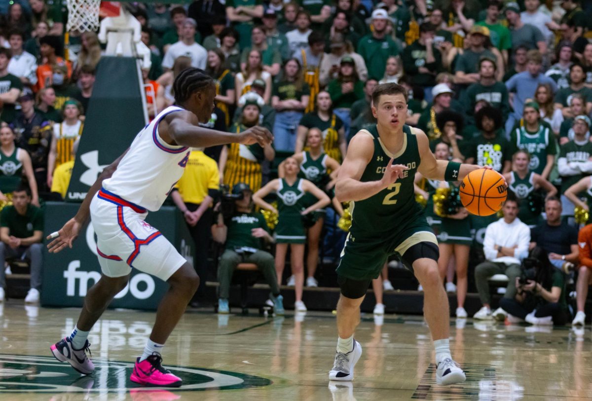 A man in an all green jersey runs by a man in an all white jersey. The man in green has the ball in his left hand.