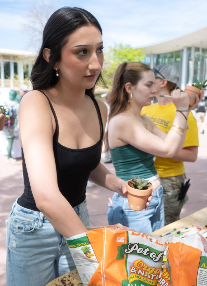 Isabella Gaytan grabs more soil for her plant as she listens to someone give instructions about taking care of the plant April 22. Potting a plant was one of the activities attendees could participate in at Colorado State University's Earth Day Festival on the Lory Student Center Plaza.