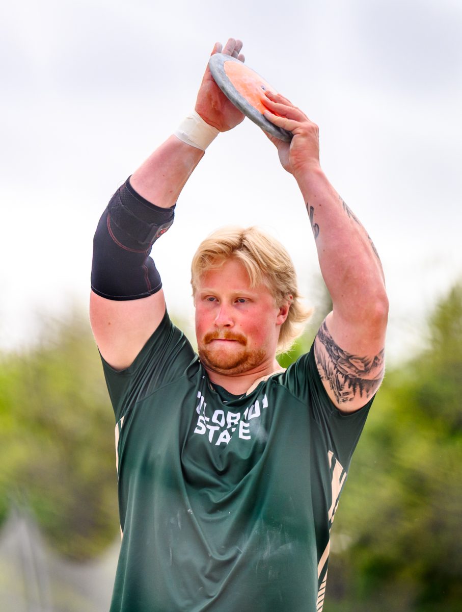 Colorado State University track and field athlete Adam Hellbom raises his hands and calls for applause before his discus throw during CSU's Border Dual Meet April 25. Hellbom placed first with a mark of 53.99 meters.