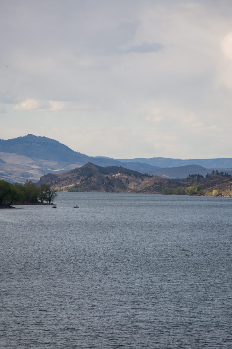 A lake sits with mountains in the background.