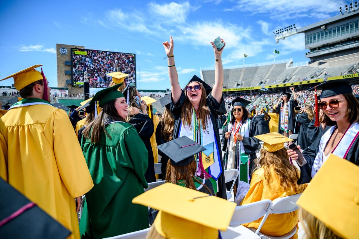 A Colorado State University graduate waves for family and friends as graduates file into the universitywide commencement ceremony in Canvas Stadium May 16. 