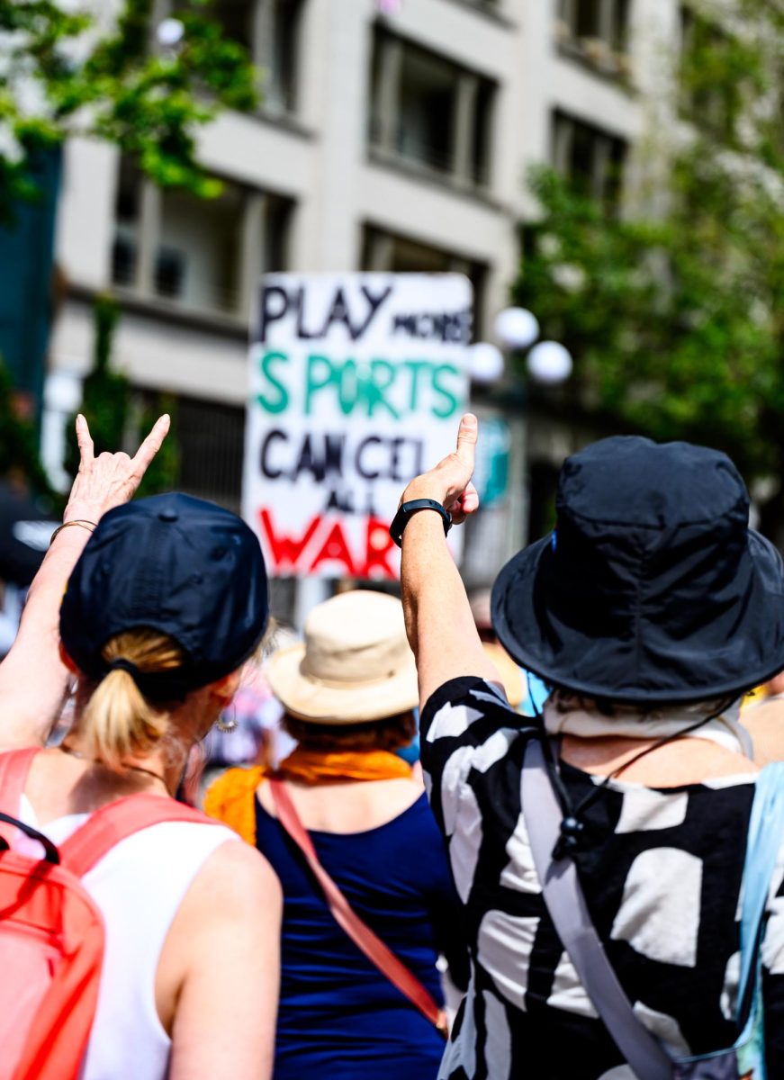 A man standing outside Seattle Stadium holds up a sign reading "Play more sports, cancel all wars," before the start of the United States' FIFA World Cup match against Australia June 19. Several people holding similar signs or speaking about different topics used the World Cup crowd to speak out about geopolitical topics that were unable to be displayed in the stadium itself due to FIFA's policies on political displays. 