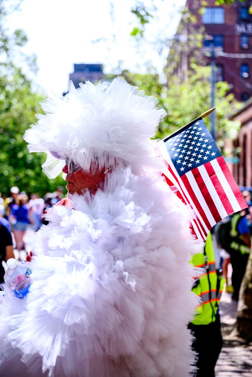 A man walks through a crowd of fans in Pioneer Square, Seattle, with an American flag over his shoulder to find a spot to watch the United States FIFA World Cup match against Australia June 19. The game was one of six held in Seattle for the tournament, with its final match being the United States loss against Belgium July 6. Belgium played three of their matches in Seattle Stadium--one group match against Egypt June 15, its Round of 32 knockout match against Senegal July 1 and its Round of 16 knockout match win against the United States. 