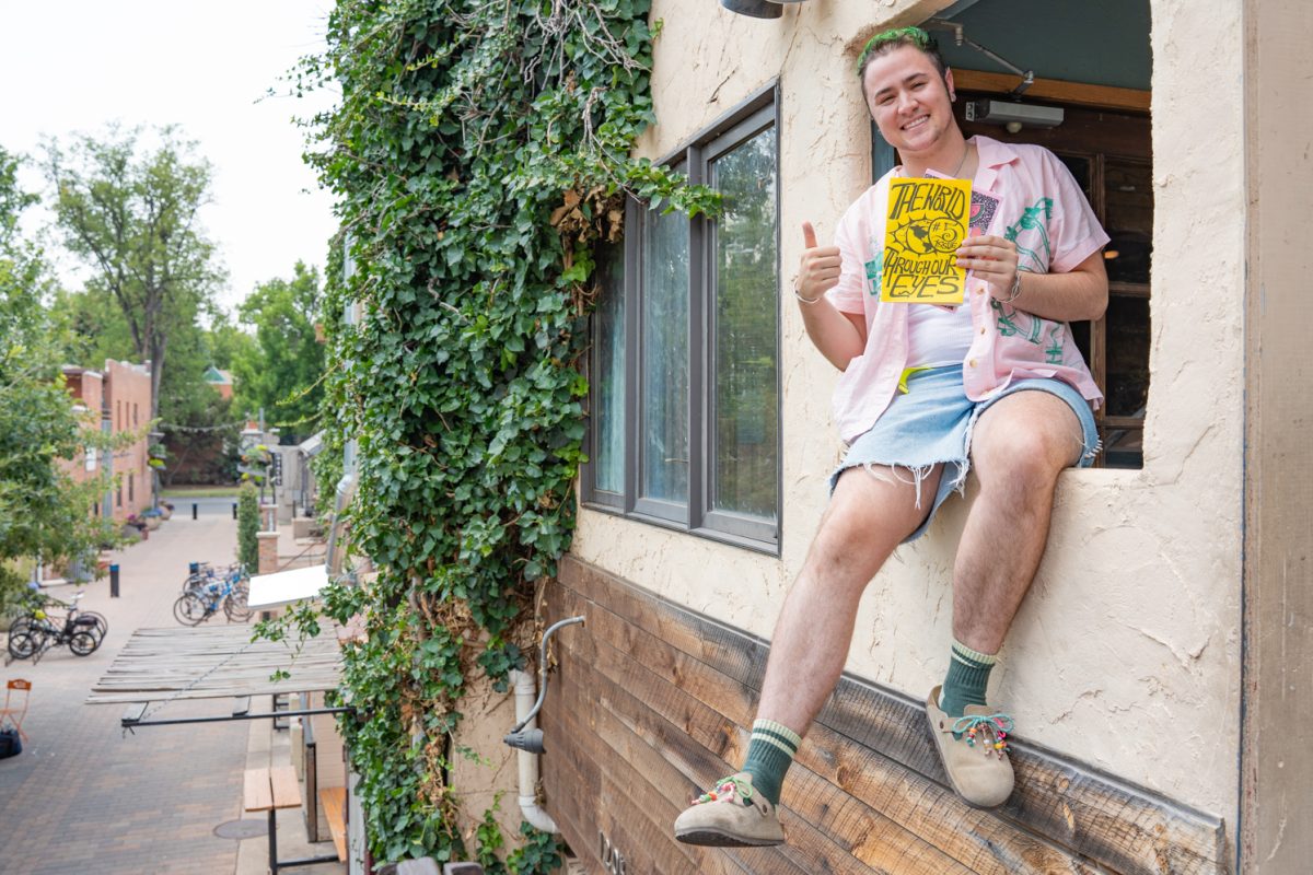 Maven Savage, the creator of the zines, “The World Through Our Eyes,” poses with their fifth issue in the series on the windowsill of The Alley Cat Cafe in Fort Collins, Colorado July 7.