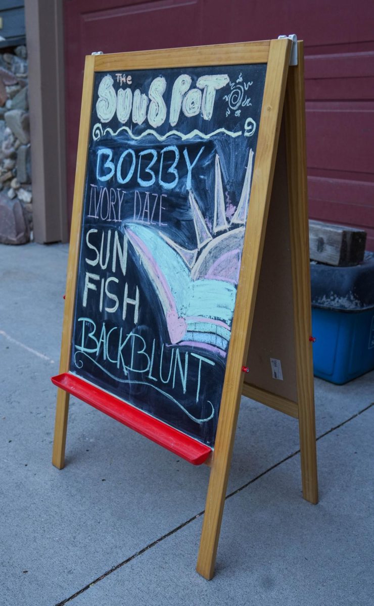 A wooden board outside of DIY concert venue Sun Spot is designed with the names of the bands playing at the house July 5. 