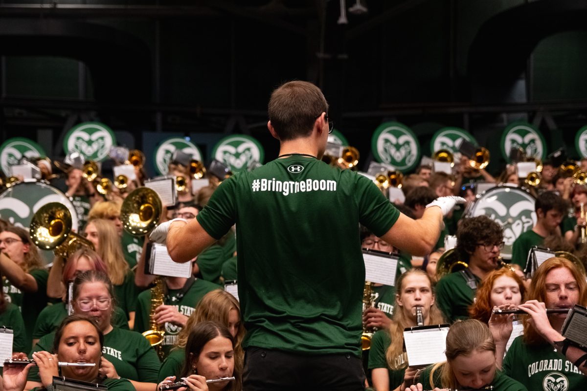The Colorado State University marching band's conductor directs his side of the band during convocation while wearing a shirt that reads "#BringTheBoom" on the back Aug. 21.