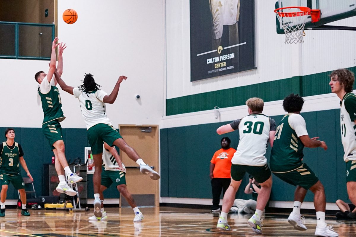Amondo Miller Jr. (18), a forward on the Colorado State University men's basketball team, shoots the ball past the arm of Carey Booth (0) during an afternoon practice in CSU's indoor practice facility Sept. 24.