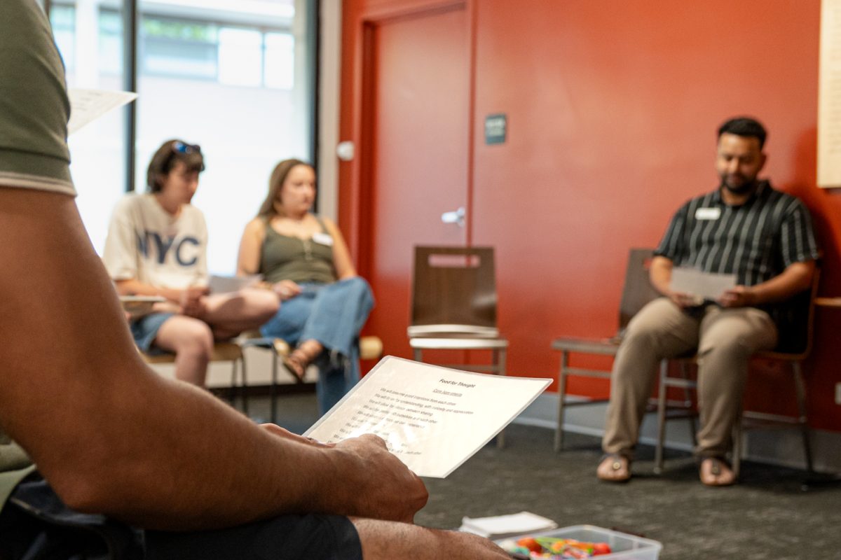 Student holds a laminated paper, reading the core agreements for the Food for Thought event at The Foundry Sept. 3. 