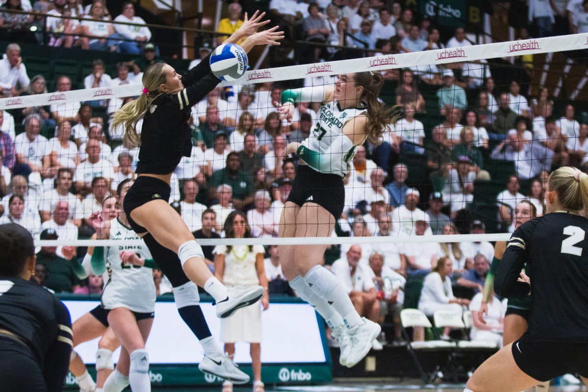 Eve Wilson (27) spikes the volleyball past the outstretched arms of a University of Colorado, Boulder player during CSU's white-out game in Moby Arena Sept. 18. Wilson's 17 attacks and 9 kills led CSU in beating CU 3-0 (25-21, 25-23, 25-15) in this game, keeping the golden spike at home.