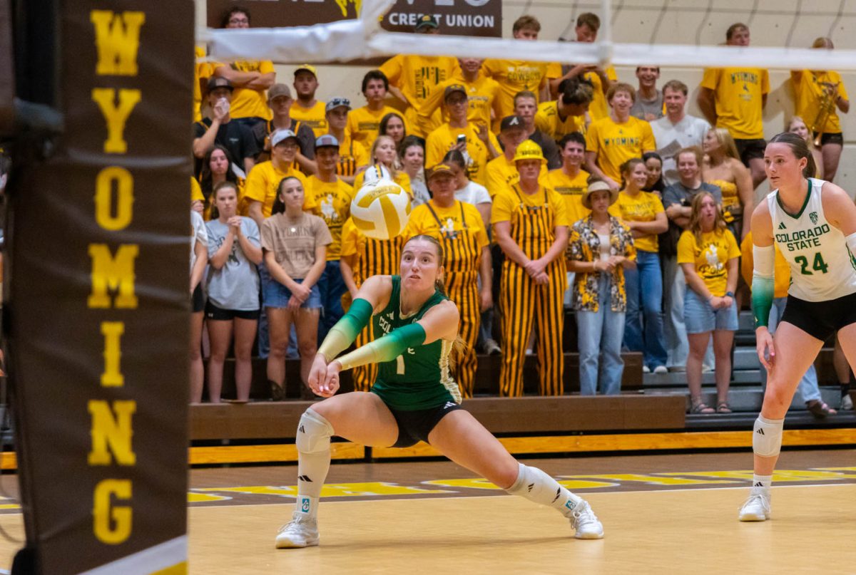 A woman in a green jersey extends her arms out toward the ball.
