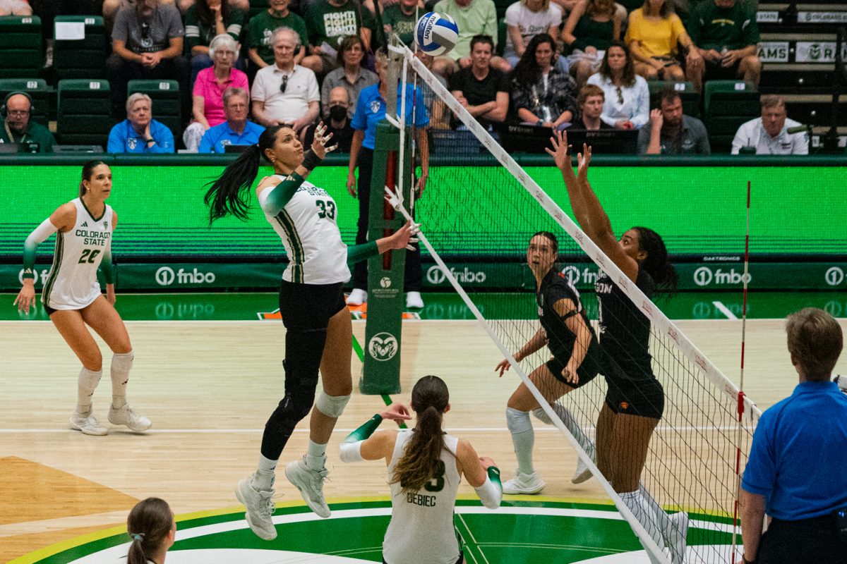 Colorado State University middle blocker Kekua Richards (33) tips the ball over the net as Oregon State University players scramble to defend in Moby Arena Oct. 10. Richards scored  8 points for the Rams, assisting them in winning the matchup against OSU 3-1.