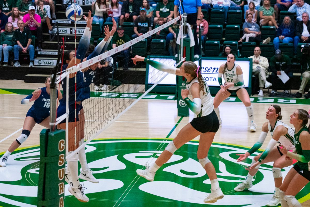 Ella Stowell (21), an outside hitter for Colorado State University volleyball, hits the ball past the arms of Utah State University's defense during a set-two attack in Moby Arena Oct. 17. Stowell led the Rams with a hit percentage of .619, scoring 14 points over 21 attacks, contributing to CSU's 3-0 sweep over the USU Aggies.