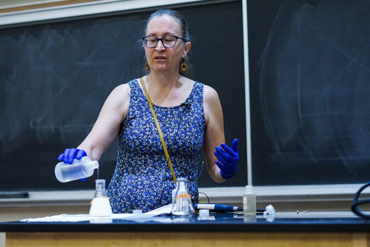 Ruth Tucker, a master instructor at Colorado State University, pours white vinegar into a beaker holding baking soda to create a chemical reaction for an in-class demonstration in the Chemistry building Oct. 1.