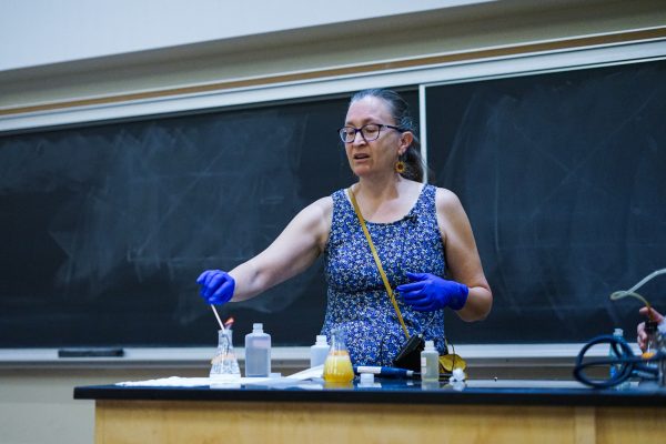 Ruth Tucker, a master instructor at Colorado State University, dips a burning wooden skewer into a beaker full of vinegar and baking soda during an in-class demonstration Oct. 1. Her students watched as the carbon dioxide produced by the chemical reaction extinguished the flame.
