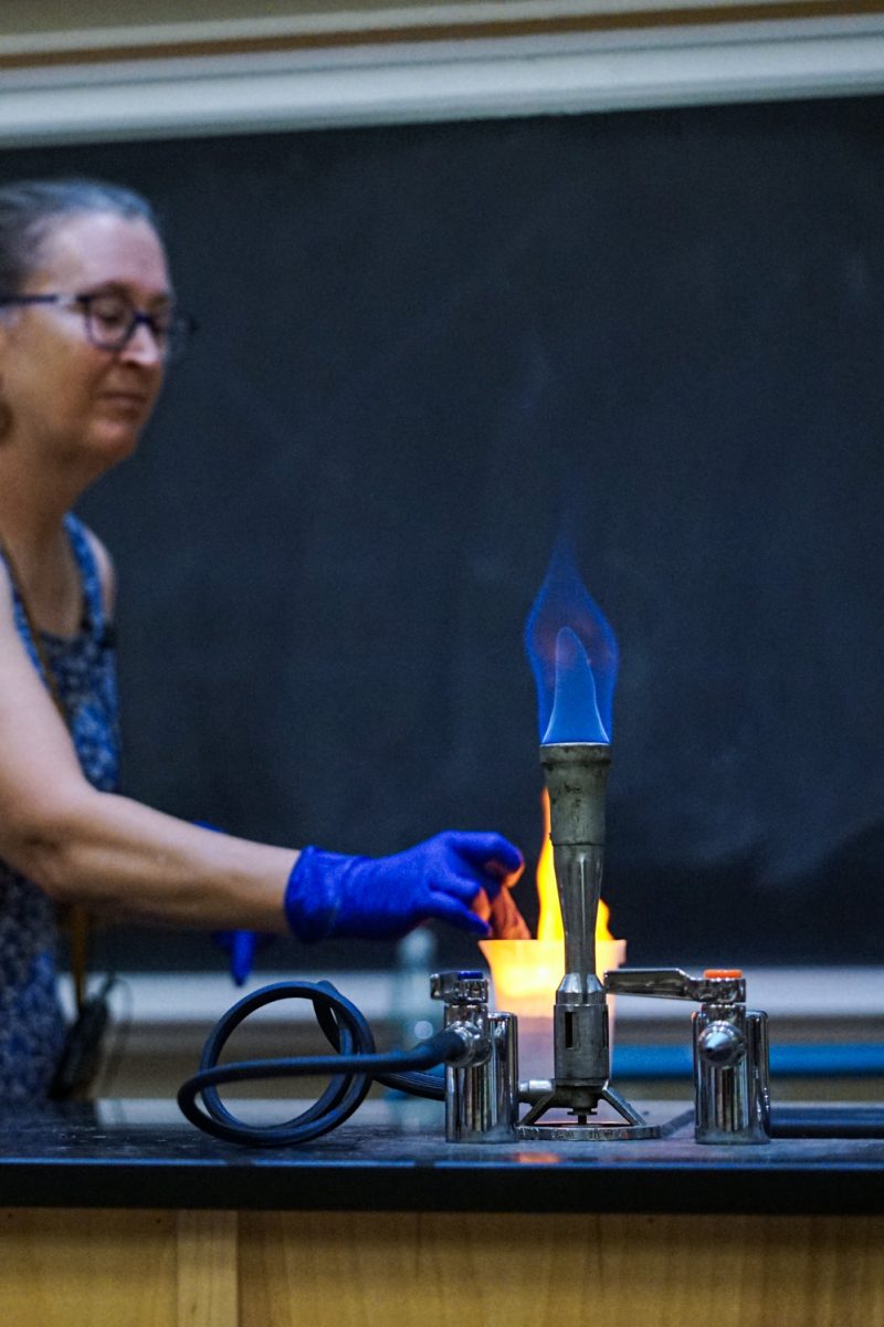 A Bunsen burner is lit in front of a beaker in a chemistry lecture taught by Ruth Tucker, who demonstrates a gas-producing chemical reaction to her students in the Chemistry building Oct. 1.