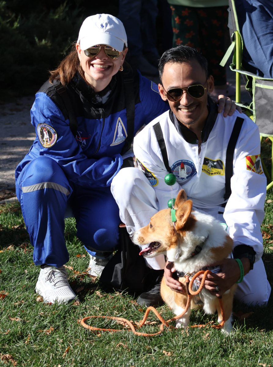 Alien pup Archie with owners Lauren (left) and Jake Howard, Civic Center Park, Oct. 3rd. "The corgi community is very cool," said Jake Howard, explaining why they returned for the third year in a row. Archie, who is young and spry at four years old, competes in herding competetions and has won two champion titles.